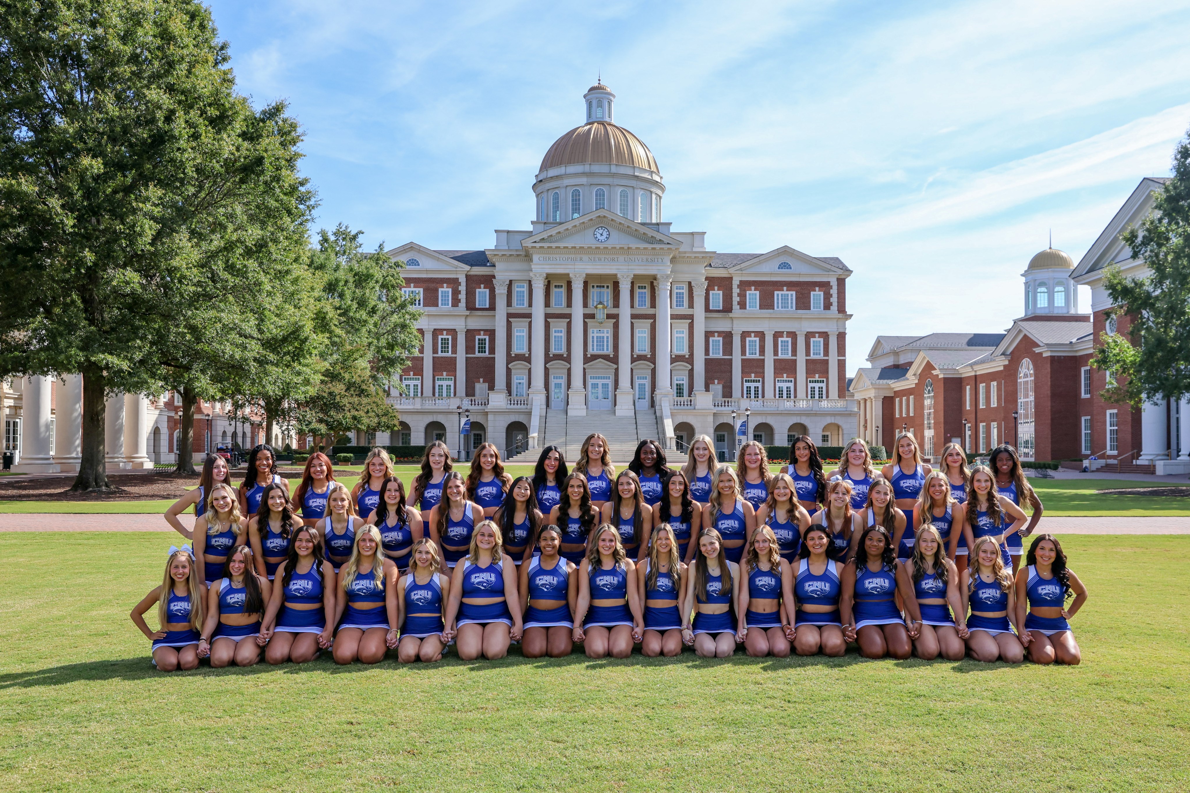 Group photo of the CNU Cheerleading team in front of Christopher Newport Hall.