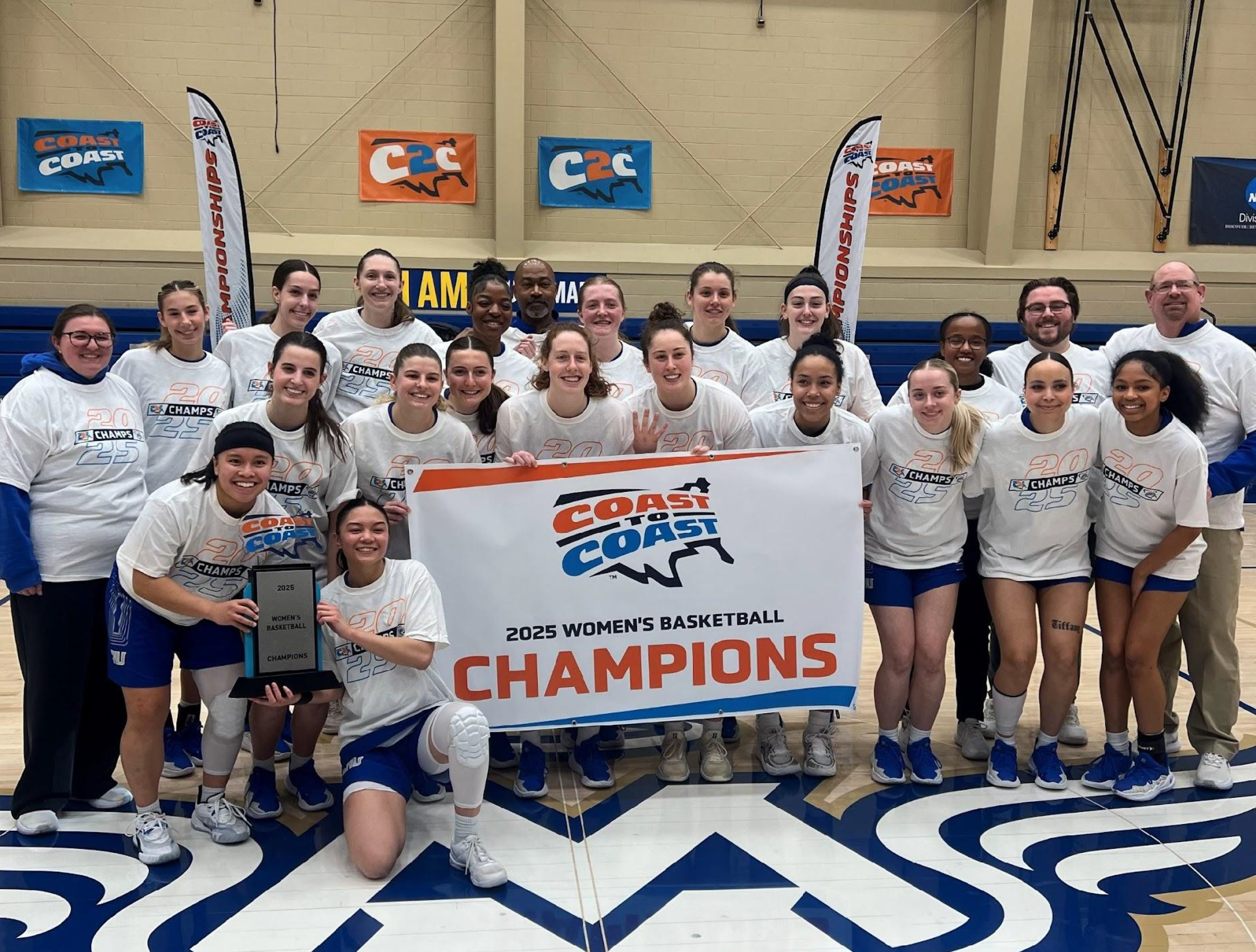 Photograph of the Women's Basketball team holding up the champions banner