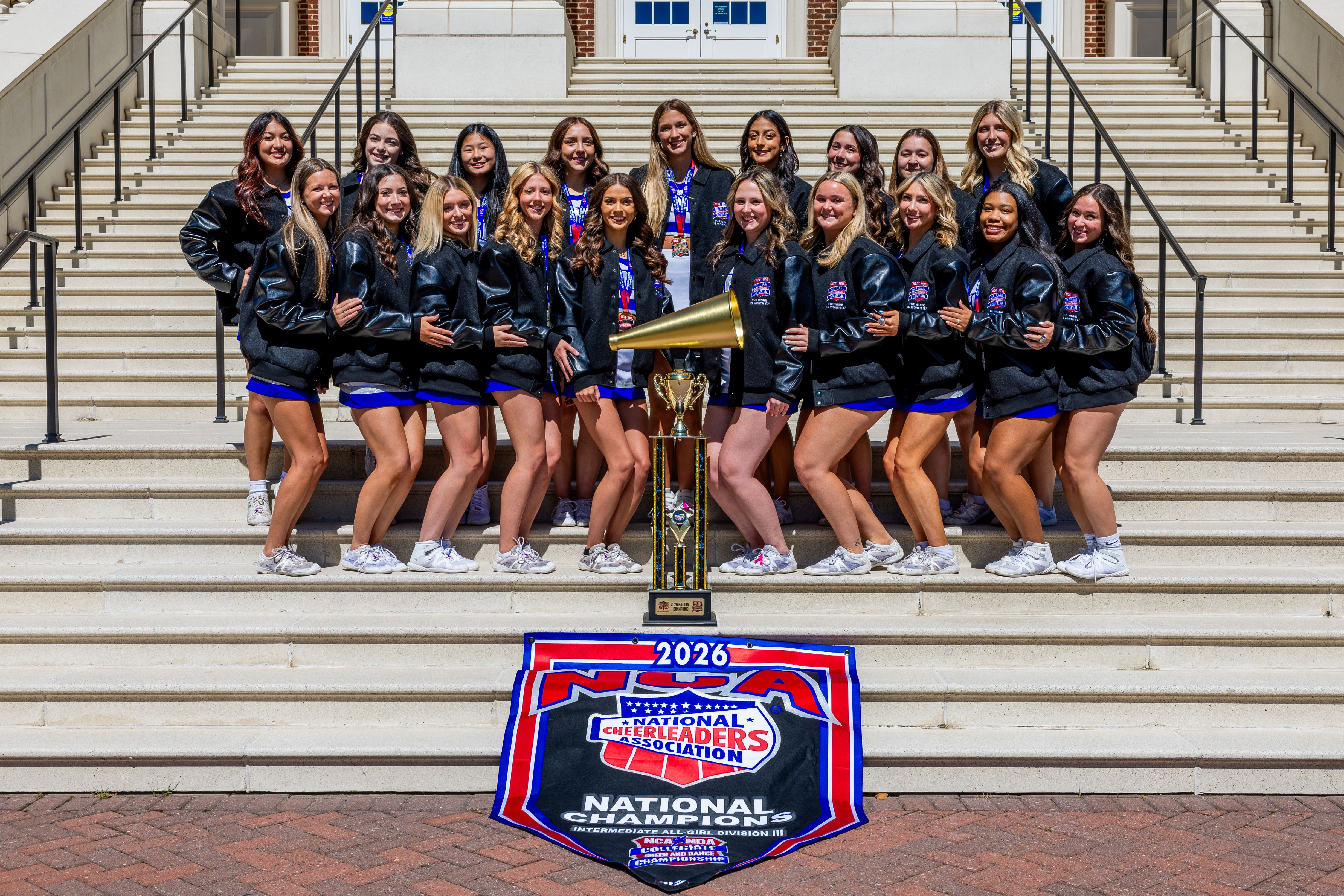 Group photo of the CNU Cheerleading team in front of Christopher Newport Hall.