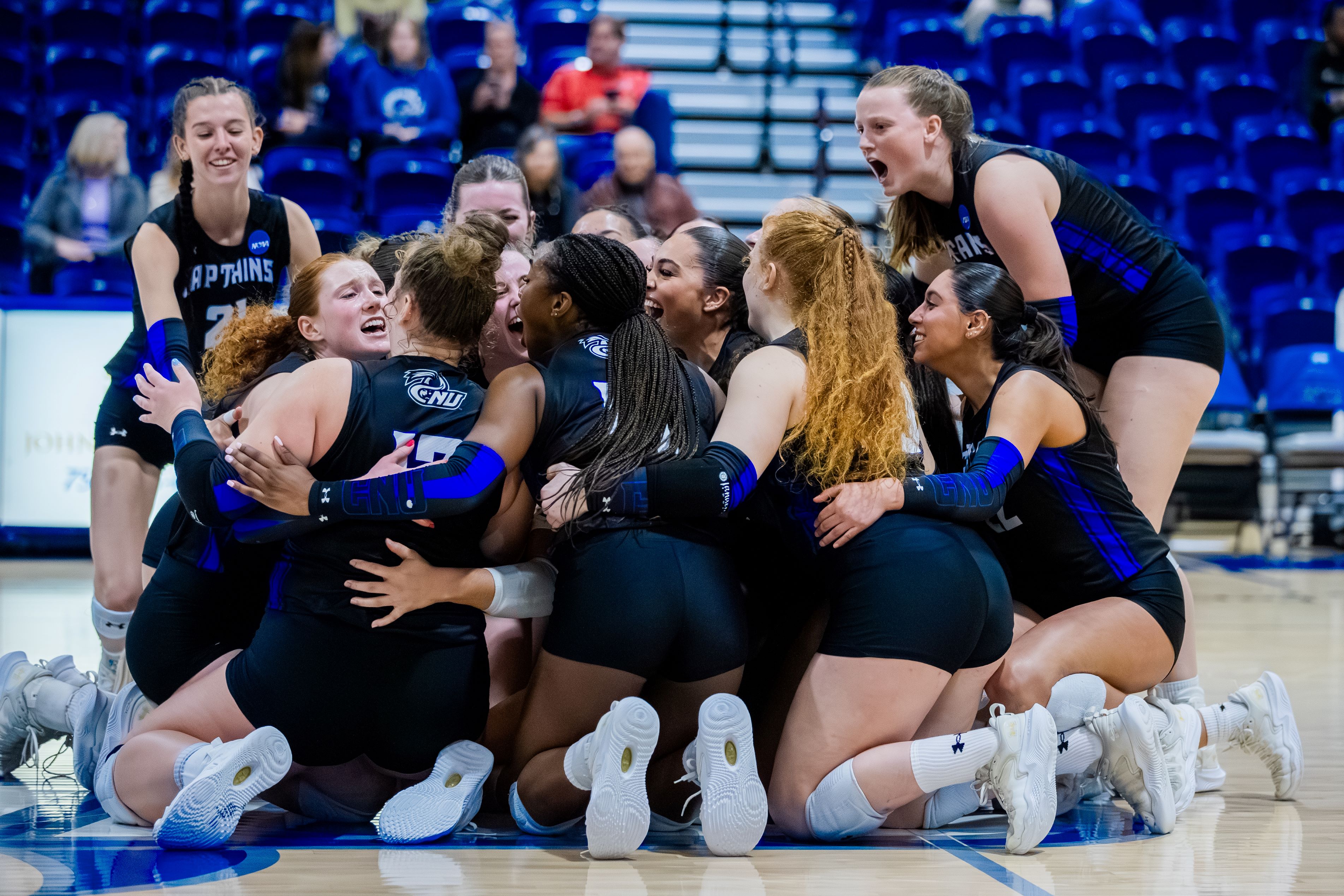 Photograph of the volleyball team celebrating on the court